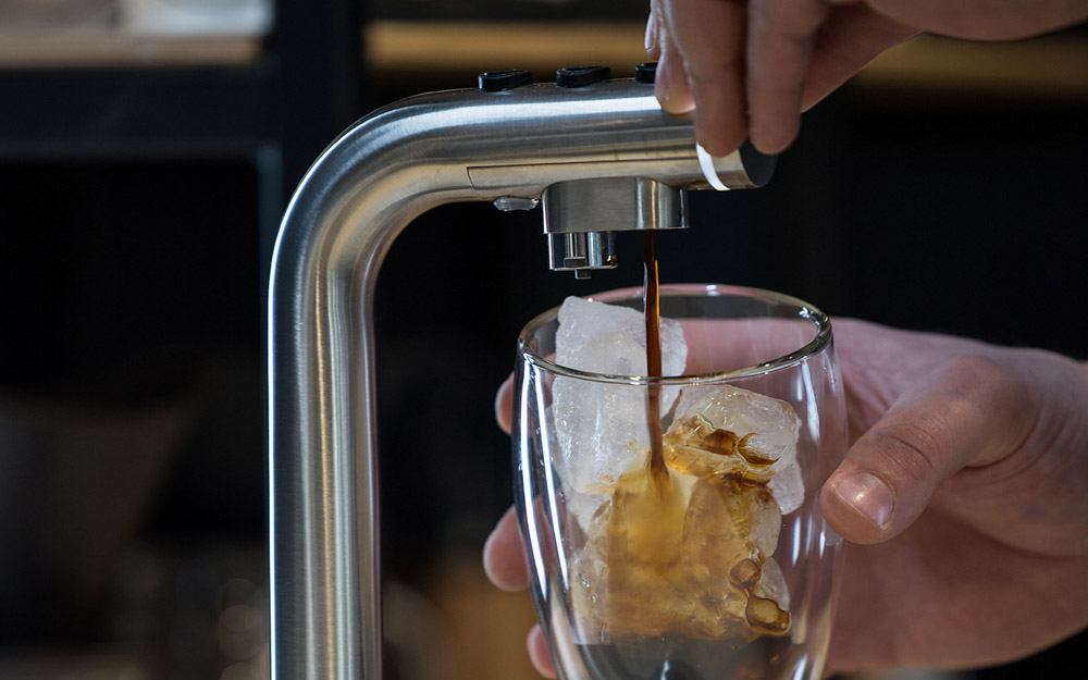 A barista dispenses coffee concentrate from the Marco POUR'D font.